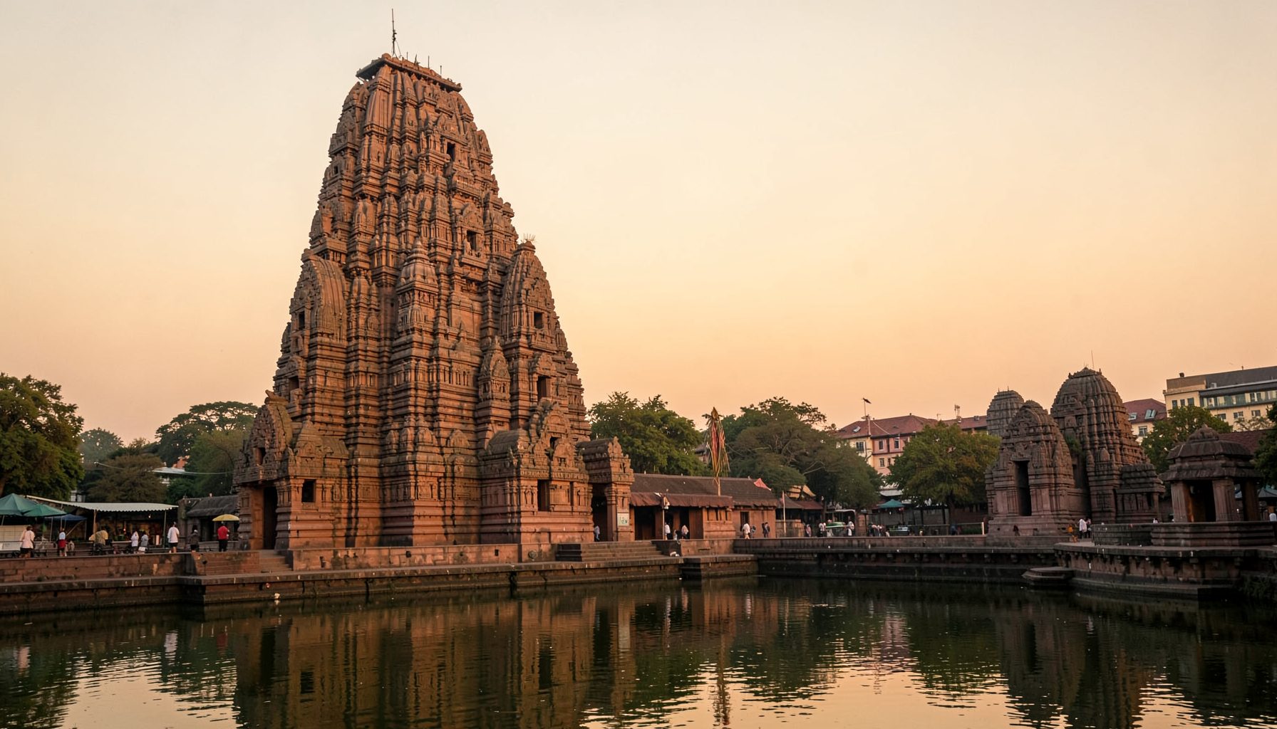 A majestic South Indian temple gopuram rising against a warm golden sky at dusk, its intricate carved tiers bathed in soft amber light